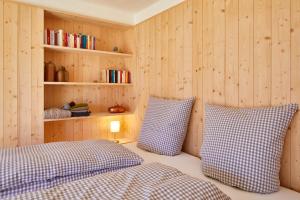 a bedroom with wooden walls and two beds with pillows at Wieshütten - fewo-badhindelang in Bad Hindelang