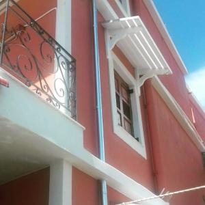 - un bâtiment rouge avec un balcon et une fenêtre dans l'établissement Sunrise House, à Parga