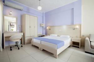 a bedroom with a bed and a desk and a chair at Giorgi's Blue Apartments in Kalathas