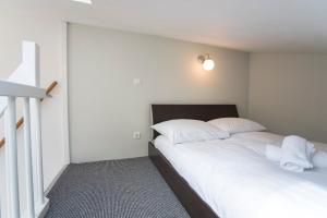 um quarto com uma cama com lençóis brancos e almofadas em New Point em Zandvoort