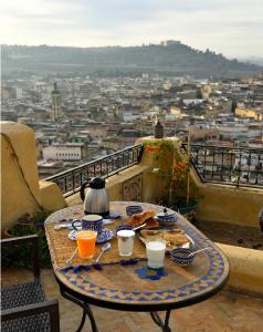 una mesa en un balcón con vistas a la ciudad en Dar Gnaoua, en Fez