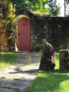 a red door in a stone wall with a rock at Pousada Casa das Fontes in Tiradentes