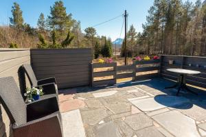 a patio with a table and chairs and a fence at Iverhjelen Near Atlantic Road in Lyngstad