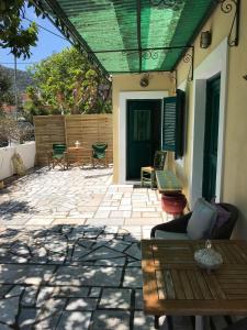 a patio with a wooden table and a green roof at Lena’s traditional villa in Ayia Evfimia