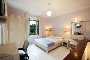 a bedroom with a bed and a desk and a window at Giorgi's Blue Apartments in Kalathas