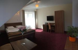 Hotel DYMINY في كيلسي: غرفة فندق بها سرير وطاولة عليها زهور