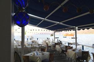 un restaurante con mesas y sillas blancas y agua en Villa Paladino - B&B e Guest House en Scilla