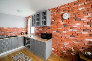 a kitchen with a brick wall and a clock on a wall at Apartament Dla Ciebie in Olsztyn