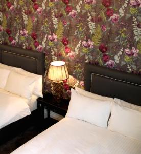 a bedroom with two beds and a wall with flowers at Kings Arms in Brentford