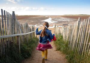 a little girl walking down a path near the beach at Victoria in Holkham
