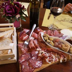 uma mesa com um prato de carnes curadas e um copo de vinho em Agriturismo Casalpiano em Pienza