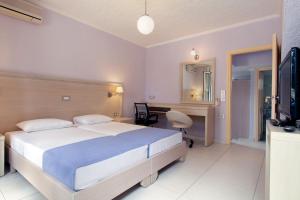 a bedroom with a bed and a desk and a television at Giorgi's Blue Apartments in Kalathas