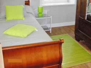ein Bett mit einem grünen Kissen und einem Tisch in der Unterkunft Holiday Home O'Petit Bonheur by Interhome in Langlerial