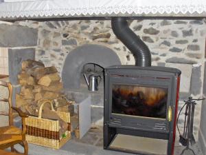 einen Steinkamin mit einem TV und einem Herd in der Unterkunft Holiday Home O'Petit Bonheur by Interhome in Langlerial
