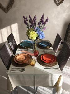 une table avec des assiettes et un vase de fleurs dans l'établissement Damo Stefania Blu Hause Marina, à Cavallino-Treporti