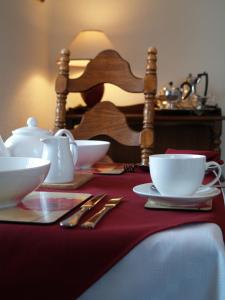 a table with two cups and saucers on a red table cloth at Cornlee in Aysgarth