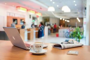 un ordenador portátil sentado en una mesa con una taza de café en ibis Valparaiso, en Valparaíso