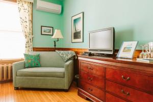 ein Wohnzimmer mit einem Stuhl und einem TV auf einer Kommode in der Unterkunft Alicion Bed & Breakfast in Lunenburg
