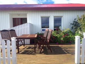 a wooden table and chairs on a deck with a house at Selalækur Country Guesthouse in Hella