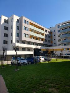 duży biały budynek z samochodami zaparkowanymi w parku w obiekcie Apartament FALA-Miodowy Dom w Kołobrzegu