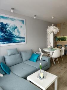 salon z niebieską kanapą i stołem w obiekcie Apartament FALA-Miodowy Dom w Kołobrzegu