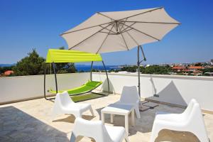 patio z krzesłami i parasolem na dachu w obiekcie Apartments Vila Moli w Bibinje