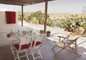 una mesa y sillas en un patio con vistas al desierto en Cortijo La Tenada Cabo de Gata en Los Albaricoques