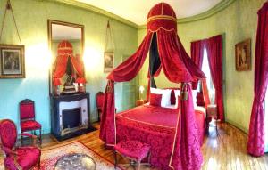 Bacilly的住宿－查托爾城堡住宿加早餐旅館，一间卧室配有一张带红色窗帘的床和壁炉