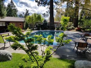 a pool with tables and chairs in a yard at Redwood Hyperion Suites in Grants Pass