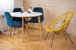 a table with four chairs and a white table with wine glasses at Apartment Merak in Mostar