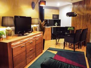 a living room with a television and a dining room at MSC Apartments Gościnny in Zakopane