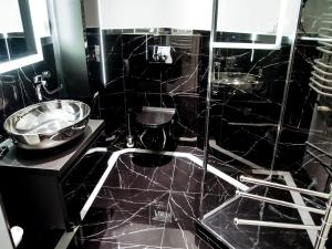 ザコパネにあるMSC Apartments Gościnnyの黒いタイル張りのバスルーム(シンク、シャワー付)
