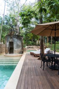 a wooden deck with an umbrella next to a swimming pool at Verde Morada in Valladolid
