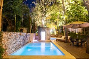 a swimming pool in a garden with an umbrella at Verde Morada in Valladolid