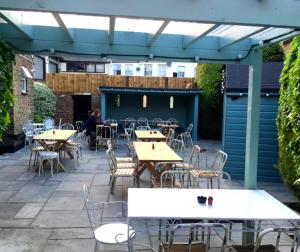 un patio al aire libre con mesas, sillas y toldo en Kings Arms en Brentford