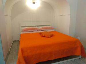 - un lit avec une couverture orange et 2 oreillers dans l'établissement GIUAMAR casa vacanza, à Polignano a Mare