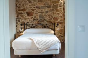Cama en habitación con pared de piedra en Casa Rural Liñeiros, en Muxía