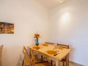 a wooden table with chairs and a vase of flowers at Apartment Douc-1 by Interhome in Seignosse