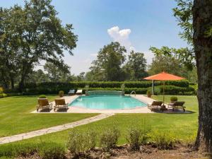 una piscina en un patio con sillas y sombrilla en Holiday Home Tenuta Farneta by Interhome, en Lucignano