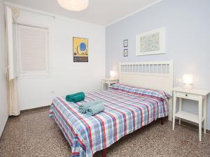 a white bedroom with a bed with a checked blanket at Apartment Sant Pol by Interhome in San Pol de Mar