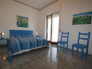 1 dormitorio con 1 cama y 2 sillas azules en Apartment Riviera Massa by Interhome, en Sorrento