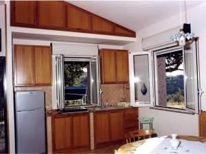 een keuken met houten kasten en 2 ramen bij Holiday Home Lulablu by Interhome in Drapia