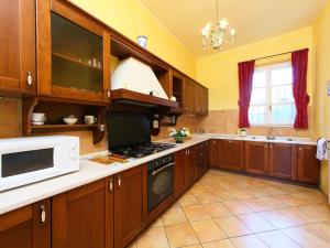a large kitchen with wooden cabinets and a microwave at Villa Paolotti by Interhome in Bettona