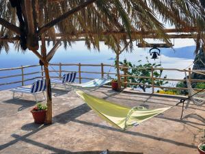 a green hammock and two chairs under a straw umbrella at Holiday Home Path of the Gods by Interhome in Pianillo