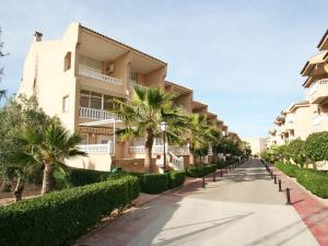 a street in front of a building with palm trees at Apartment Residencial El Pinar by Interhome in Guardamar del Segura
