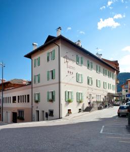 a large white building with green shutters on a street at Albergo Tuenno in Tuenno