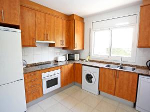 a kitchen with wooden cabinets and a washer and dryer at Villa Villa Llobeta by Interhome in Les tres Cales