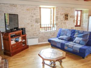 a living room with a blue couch and a tv at Holiday Home Sourdoire by Interhome in La Chapelle-aux-Saints