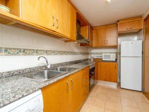 a kitchen with wooden cabinets and a white refrigerator at Apartment Menorca-3 by Interhome in Balcon del Mar