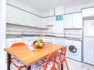 リョレート・デ・マルにあるApartment Fleming by Interhomeのキッチン(木製テーブル、オレンジチェア付)